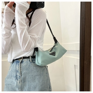 Detail shot of a mint green hobo bag with a black shoulder strap and metal triangle logo
