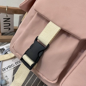 Detailed shot of pink canvas backpack featuring beige straps and durable plastic buckles