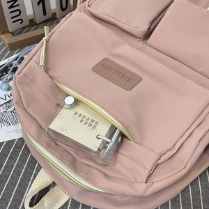 Close-up of pink canvas backpack with multiple pockets and brand tag on textured table