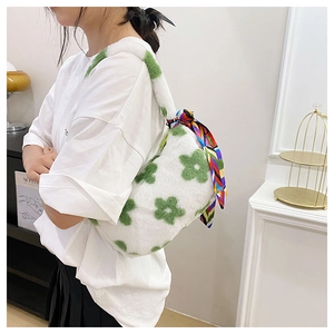 Close-up of white plush shoulder bag with green floral patterns and decorative silk scarf