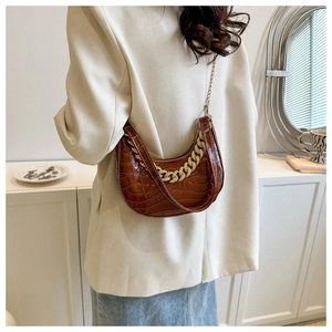 Bolso hobo marrón con grabado de cocodrilo y correa de cadena dorada en una modelo