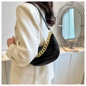 Detalle del bolso negro con patrón de cocodrilo y correa de cadena dorada decorativa