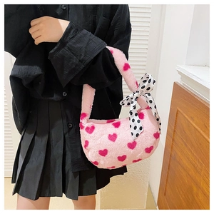 Close-up of pink plush handbag featuring red hearts and a black polka dot bow