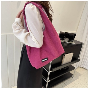 Détail du sac cabas en velours côtelé rose avec étiquette de mode sur l'épaule