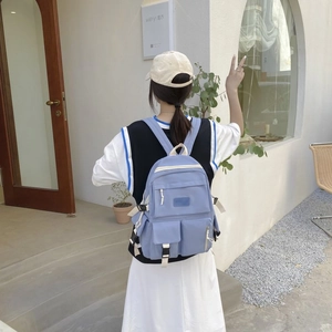 Detail view of a light blue nylon backpack with multiple functional pockets and buckles