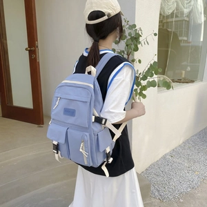 Detailed side view of the light blue backpack with multi-pocket design on the model