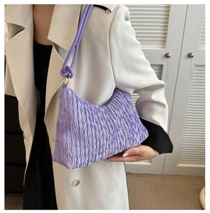 Detail of purple pleated texture handbag with golden metal ring and white blazer matching