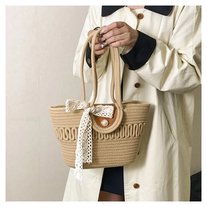 Detail view of khaki woven tote bag featuring a white lace bow and pearl snap button