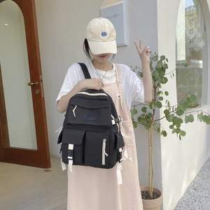 Detail of durable black nylon backpack with multi-pocket design and white buckles on the street