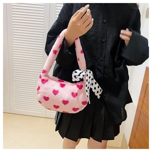 Detail of pink plush handbag with red heart patterns and decorative polka dot silk scarf