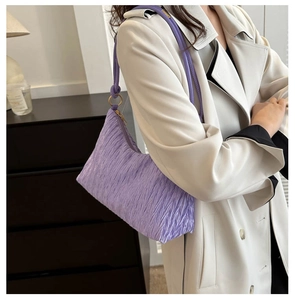 Detail of lavender pleated shoulder bag showing ruched texture and golden metal ring