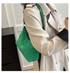 Detail showing the bright emerald green pleated texture and shiny silk-like fabric of the bag