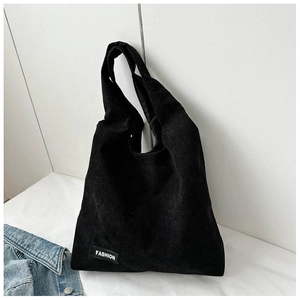 Détail du sac cabas en velours côtelé noir montrant la texture et l'étiquette mode