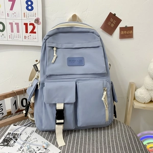 Detail of grey-blue nylon backpack showing buckled front pockets and creamy zipper tapes