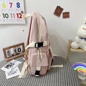 Detail view of pink multi-pocket backpack side structure with buckles and woven straps