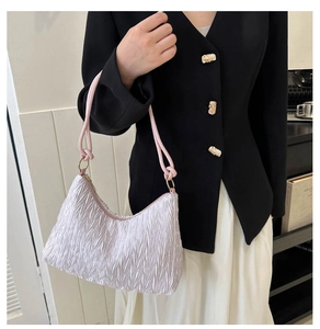 Detail of pleated shoulder bag with gold metal rings and elegant lavender fabric
