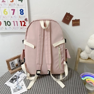 Pink student backpack detail showing anti-theft back pocket and adjustable white straps