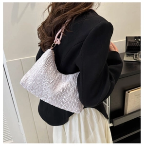 Detail of white pleated hobo shoulder bag with purple knotted rope strap on model