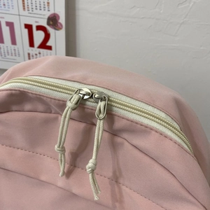 Detail view of pink student backpack showing dual zippers and durable braided rope pulls