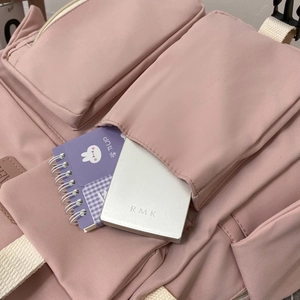 Detailed close-up of multi-pocket storage nylon backpack in dusty rose finish