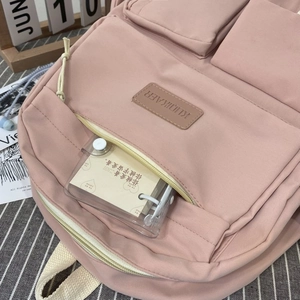 Detail of pink multi-pocket backpack with functional compartments and decorative inserts