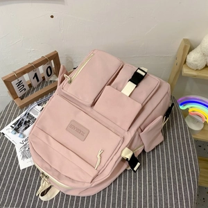Detail view of pink nylon school backpack with multiple pockets and black buckle straps