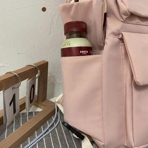 Close-up of side pocket on pink student backpack holding a 500ml coffee bottle