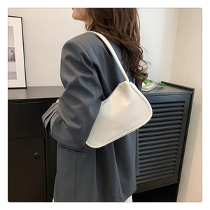 Detailansicht einer weißen strukturierten Schultertasche kombiniert mit grauem Blazer