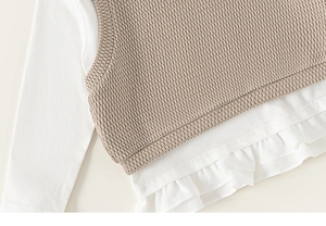 Detailansicht der Strickweste und des Rüschensaums des langärmeligen Mädchen-Oberteils