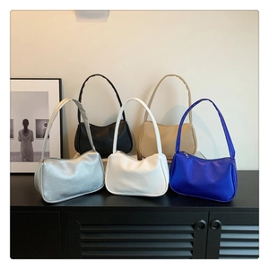 Minimalistische Halbmond-Schultertaschen in fünf Farben auf Holzoberfläche mit Porträthintergrund