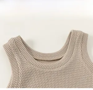 Detaillierte Nahaufnahme des klassischen Rundhalsausschnitts einer beigen Baby-Strickweste