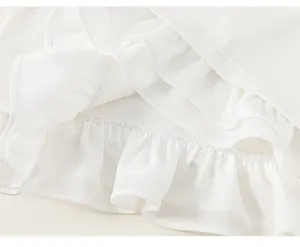 Detail eines mehrlagigen Rüschensaums an einem weißen Langarmshirt für Mädchen mit Nähten