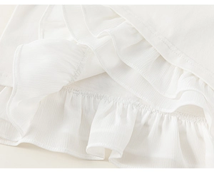 Makroaufnahme von dreilagigen weißen Chiffon-Rüschen am Saum mit sauberen Nähten für Kinder