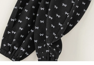 Close-up detail of girls black casual pants featuring white bowknot patterns and elastic cuff