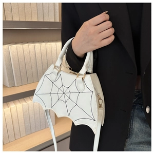 Detail der weißen Handtasche in Spinnennetzform mit schwarzen Nähten und Goldakzenten