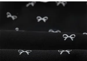 Close-up of black knitted fabric with cute silver bow prints for girls casual pants