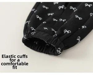 Detail of children's black pants with white bow prints and elastic ribbed cuffs