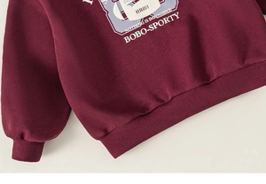 Detail of ribbed hem and Nothing Is Impossible letter print on burgundy sweatshirt