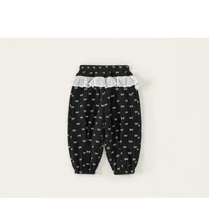 Detail of girls black pants featuring white bow prints and delicate lace waistband trim