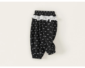 Detail view of girl's black trousers with white bow prints and lace waistband
