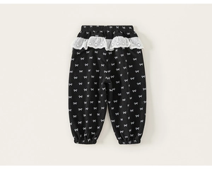 Close-up of girls' black trousers featuring white bow prints and delicate lace details