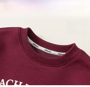 Close-up of ribbed crew neck and inner neck tape on burgundy cotton sweatshirt