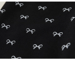 Detail of silver bow print on black cotton fabric for girl's autumn trousers
