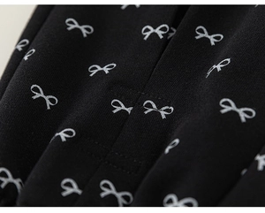 Close-up of black cotton pants featuring white bow prints and delicate ruffle details