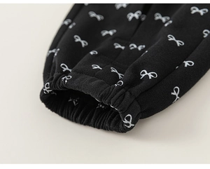 Detail of black girl's trousers showing elasticated cuffs and white bow pattern print