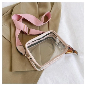 Detail der transparenten PVC-Umhängetasche mit rosa Gurt und dekorativem Seidenschal