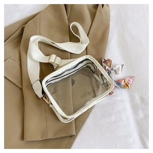 Detail einer transparenten PVC-Umhängetasche mit weißem Gurt und dekorativem Seidenschal
