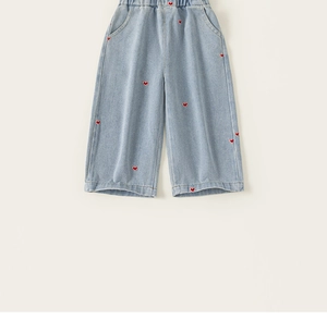 Détail d'un jean large bleu clair pour fille avec broderie de cœurs rouges et taille élastique