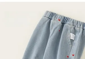 Détail du pantalon en jean pour bébé avec taille élastique et broderie coeur rouge sur bleu