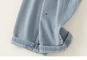 Détail de la broderie cœur rouge sur denim bleu clair avec ourlet replié stylé